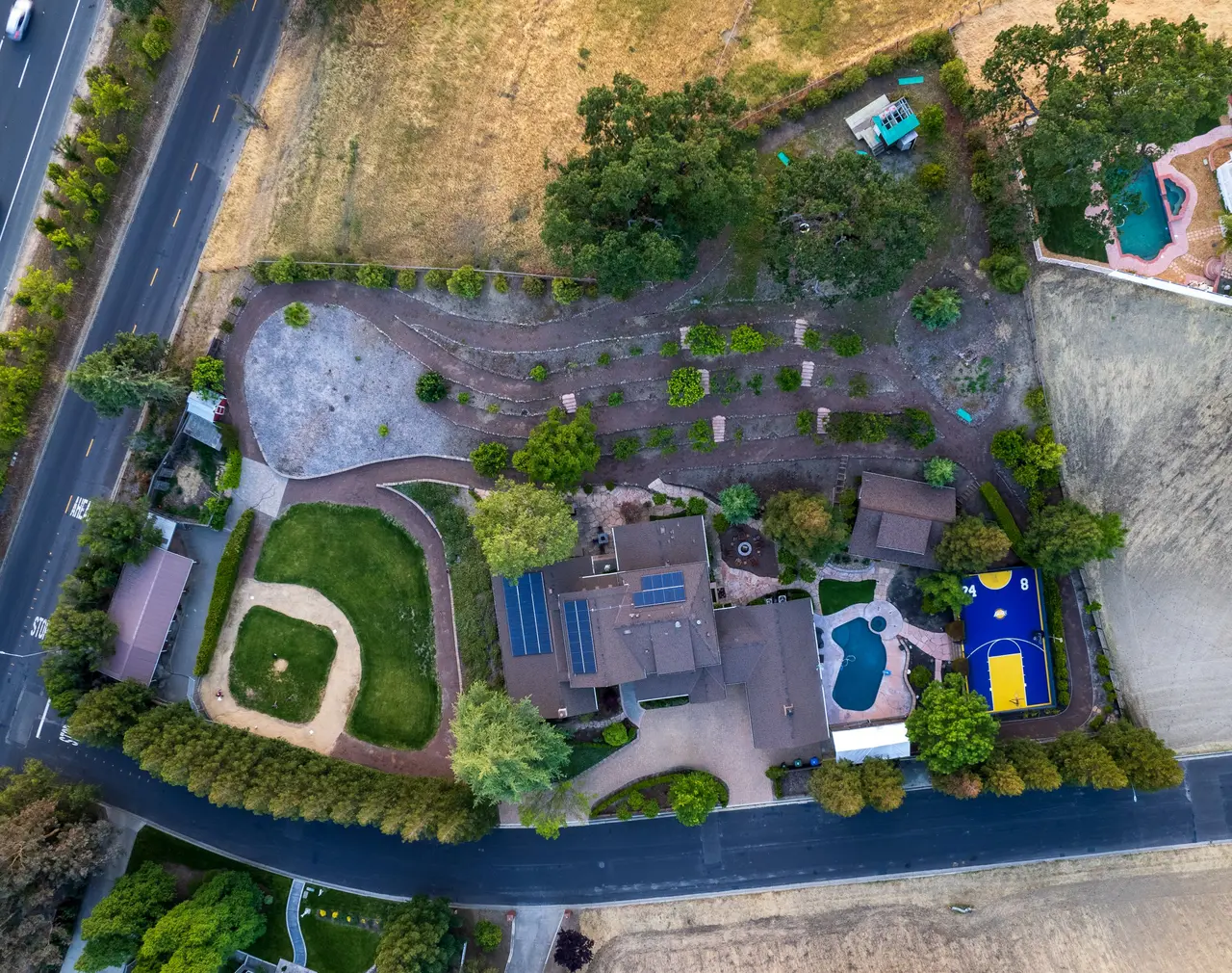Aerial view of the home, pool, sport court, lawn, and terraced gardens