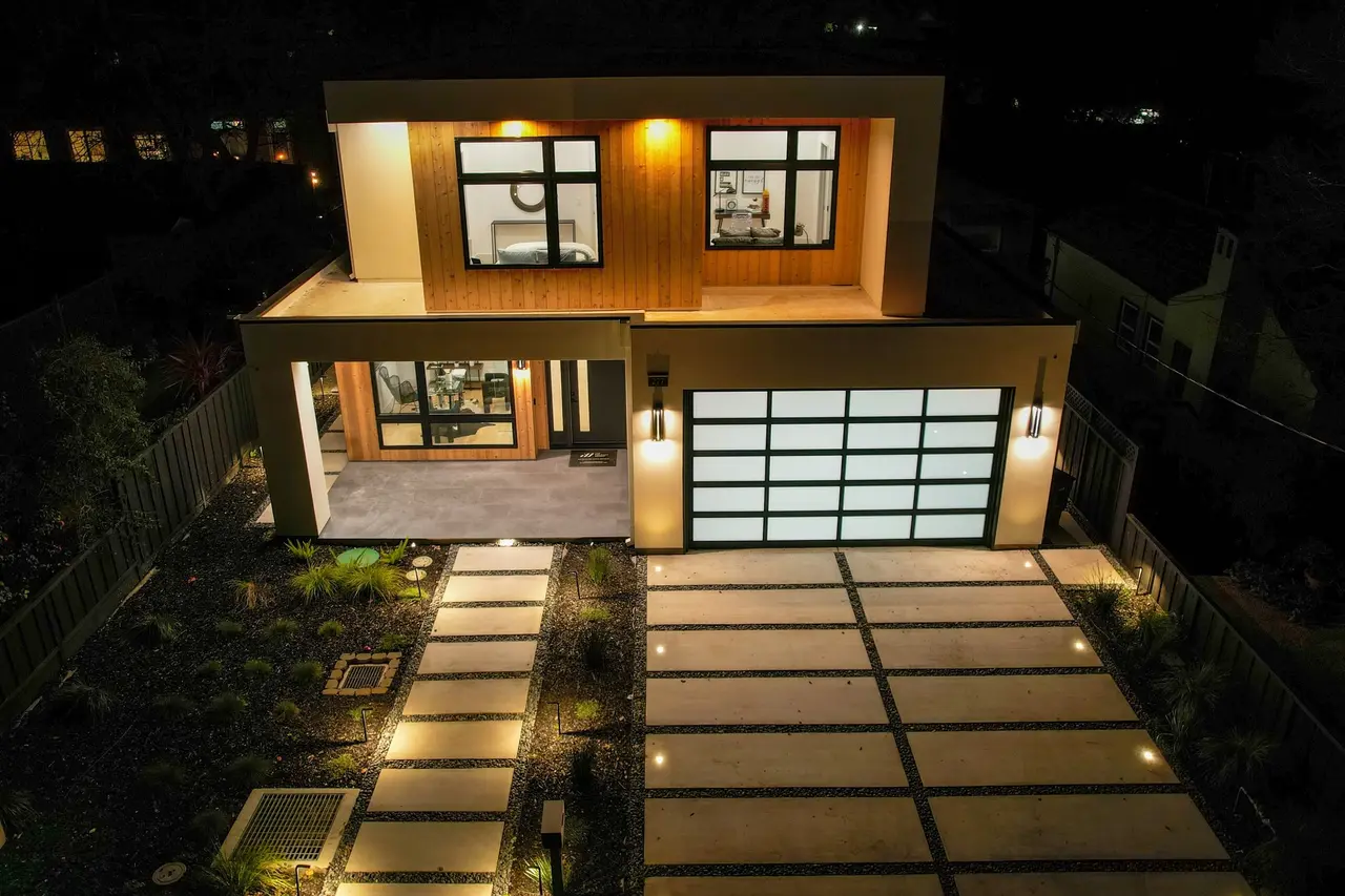Front of the home at night with a lit paver walkway and a wide driveway