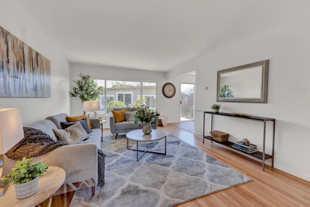 Living room seating area with a patterned rug and a glass door to the yard