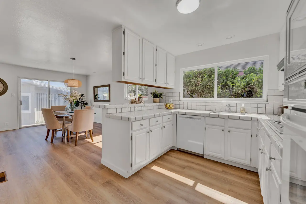 White kitchen with tile counters that opens to the dining area
