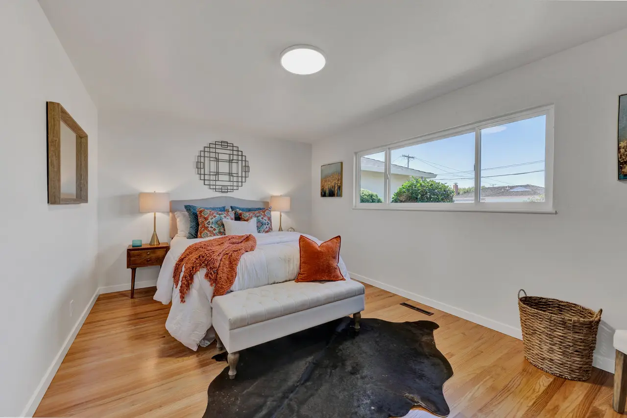 Bedroom with hardwood floors and a wide window