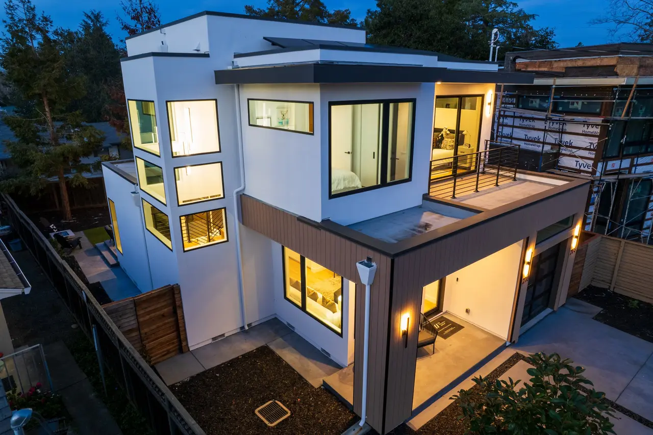 Side of the home at dusk with tall windows and an upper deck