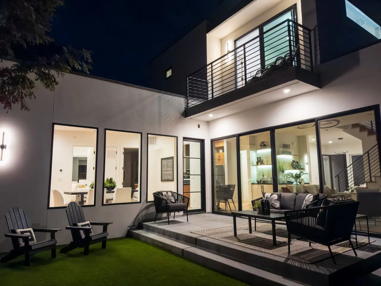 Patio at night with lounge seating and glass doors into the living area