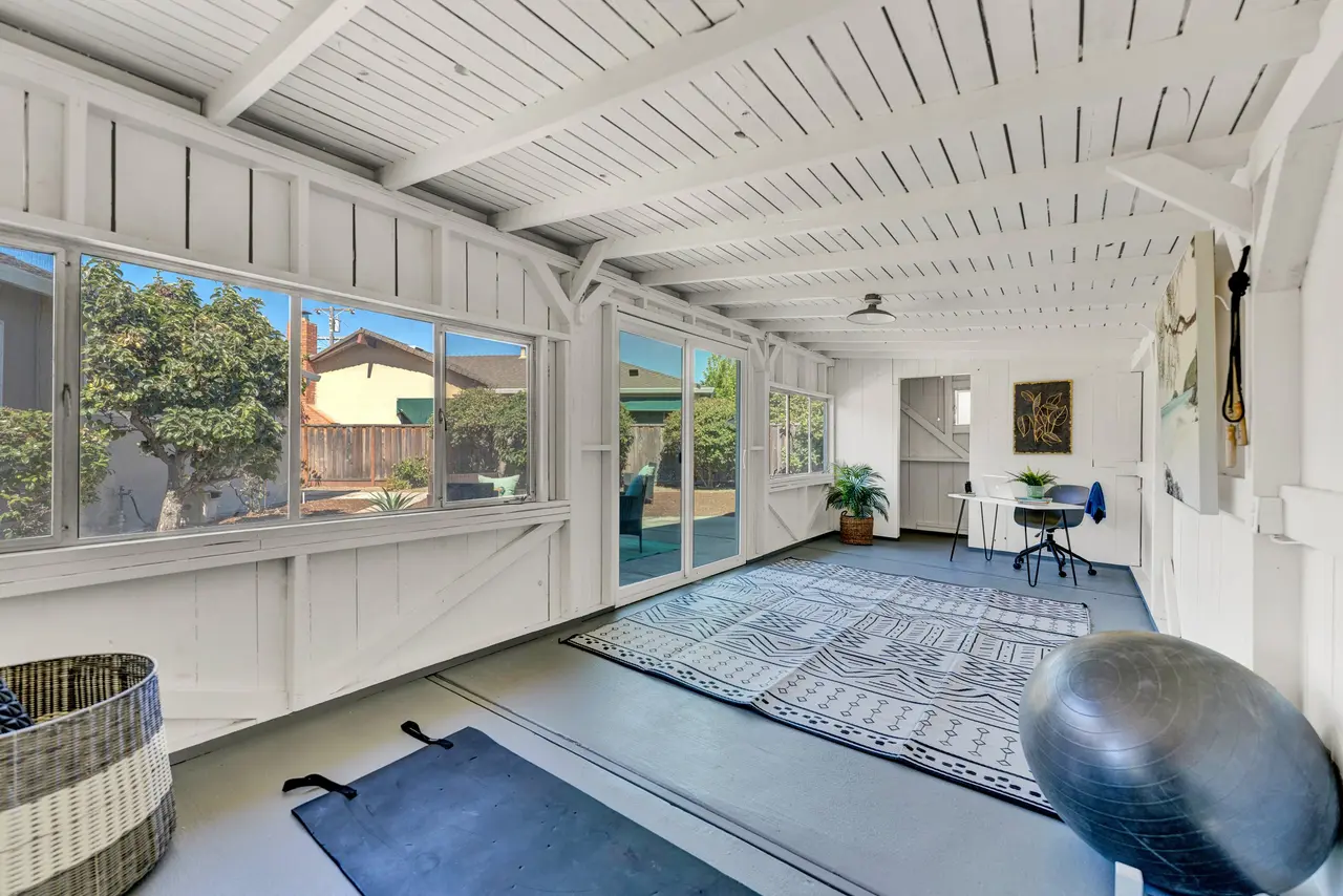 Sunroom with white wood paneling, exposed beams, and walls of windows