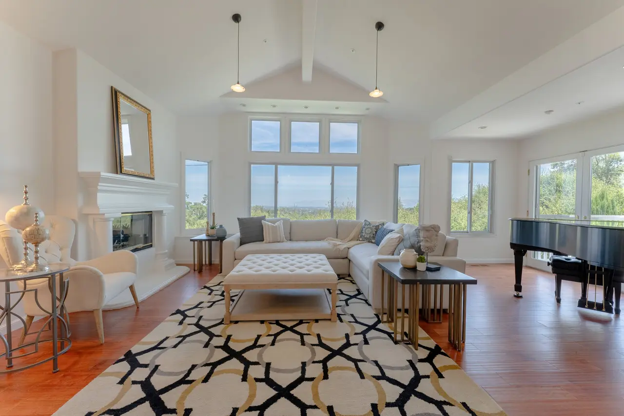 Living room with a vaulted ceiling, a fireplace, and a wall of windows
