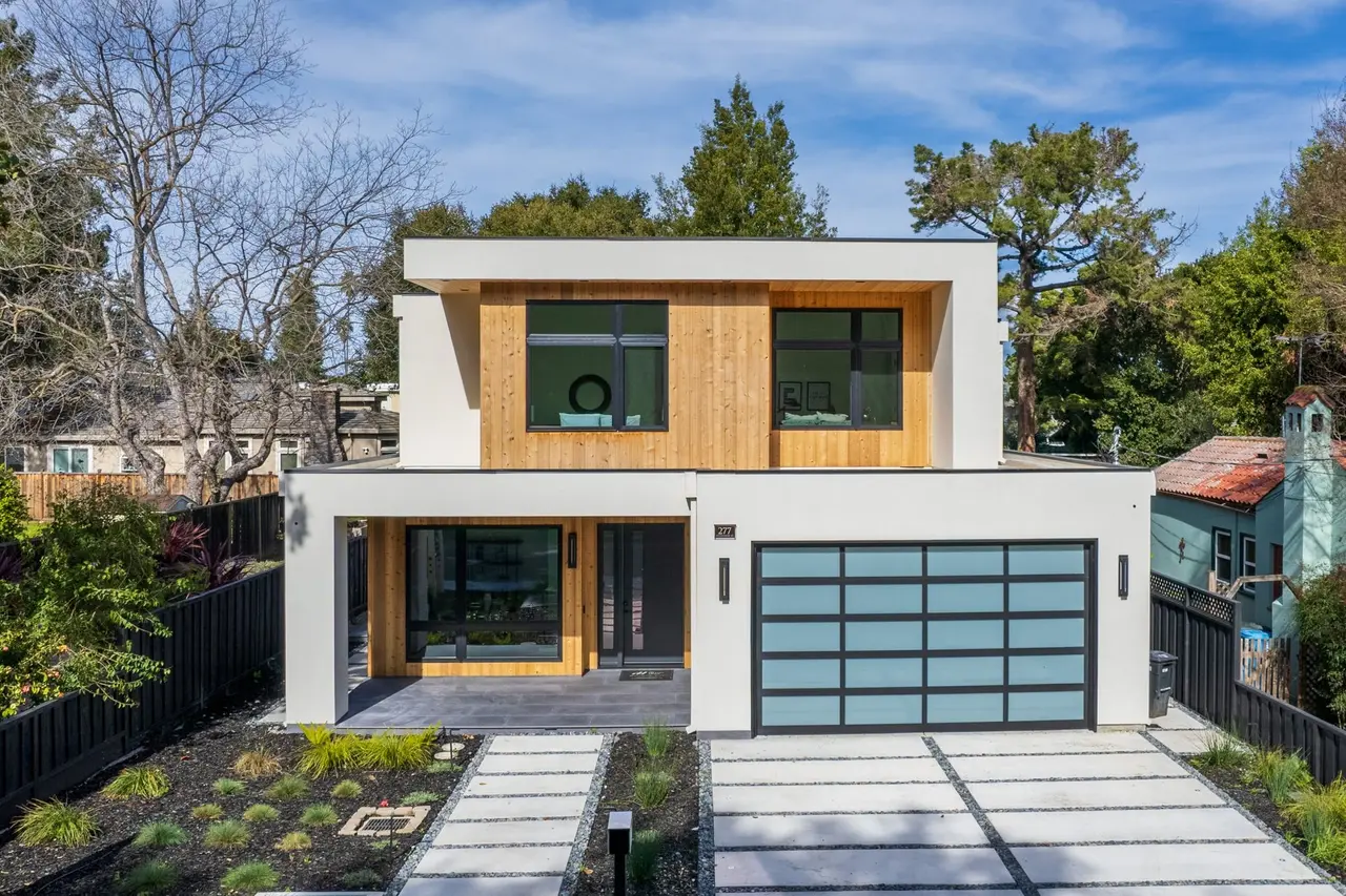 Daytime view of the front with wood and stucco siding and a glass garage door